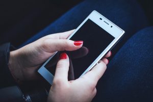 Mobile phone being used by a woman with red painted fingernails, accessing her travel apps