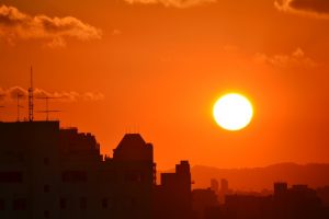 Photo of the setting sun on a city landscape. Business travels are hard when it's hot outside.