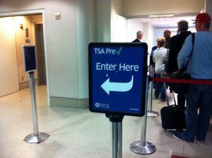 TSA PreCheck sign showing the way to an empty pathway, next to a line packed with people.