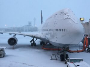 A Lufthansa airplane covered in snow. This is a common sight if you take a lot of winter business travel trips.