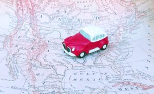 Photo of a toy car on a map. A road trip is a great way to experience domestic travel.