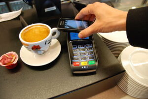 Someone paying with their phone, one form of contactless payment