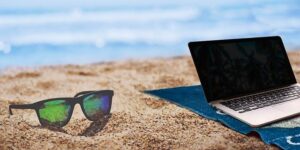 Photo of a computer on a beach. Sometimes you have to work when you're on vacation, but you can reduce the time you spend doing it.