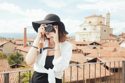 A woman taking a photo in front of a tourist destination. She looks like she could be a frequent traveler. You could be too.