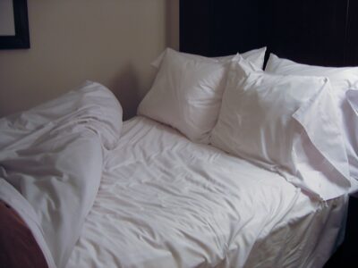 A hotel bed with white sheets. This is one of the hotel secrets every traveler should know.